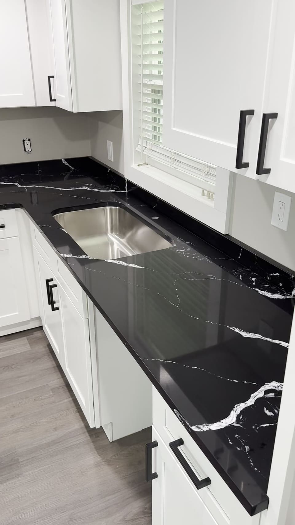 Black countertop with white veining and an undermount sink on white shaker cabinets