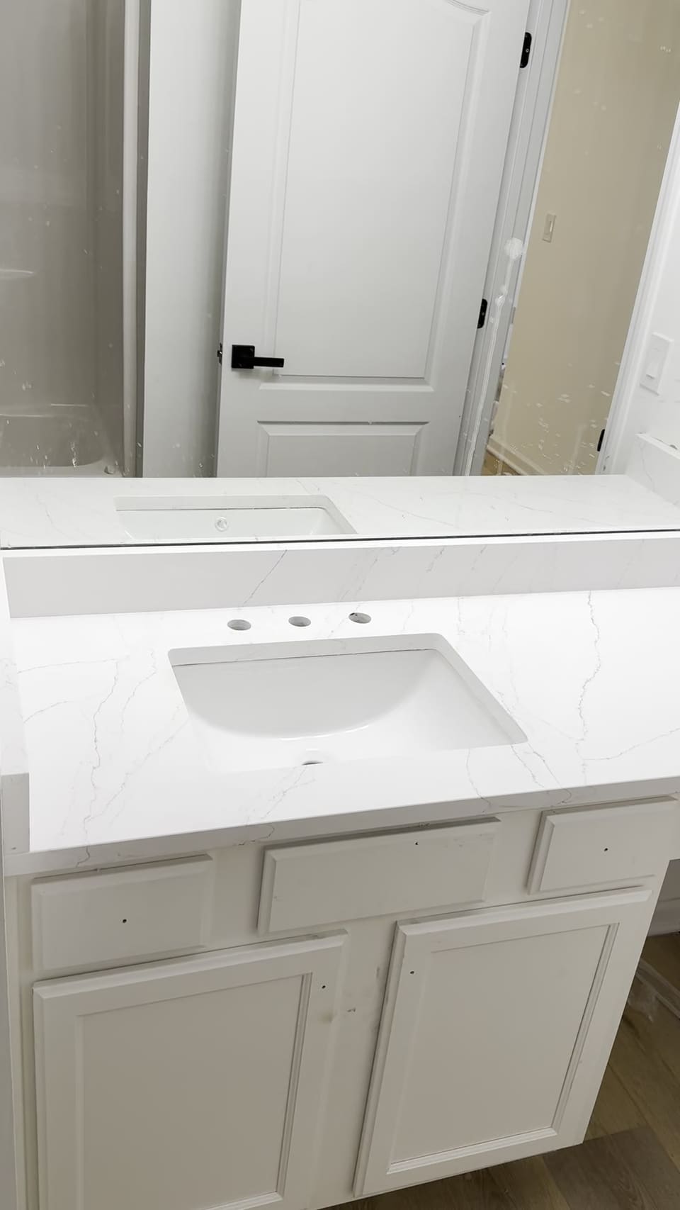 Long white stone vanity top with an undermount sink and a lowered makeup counter