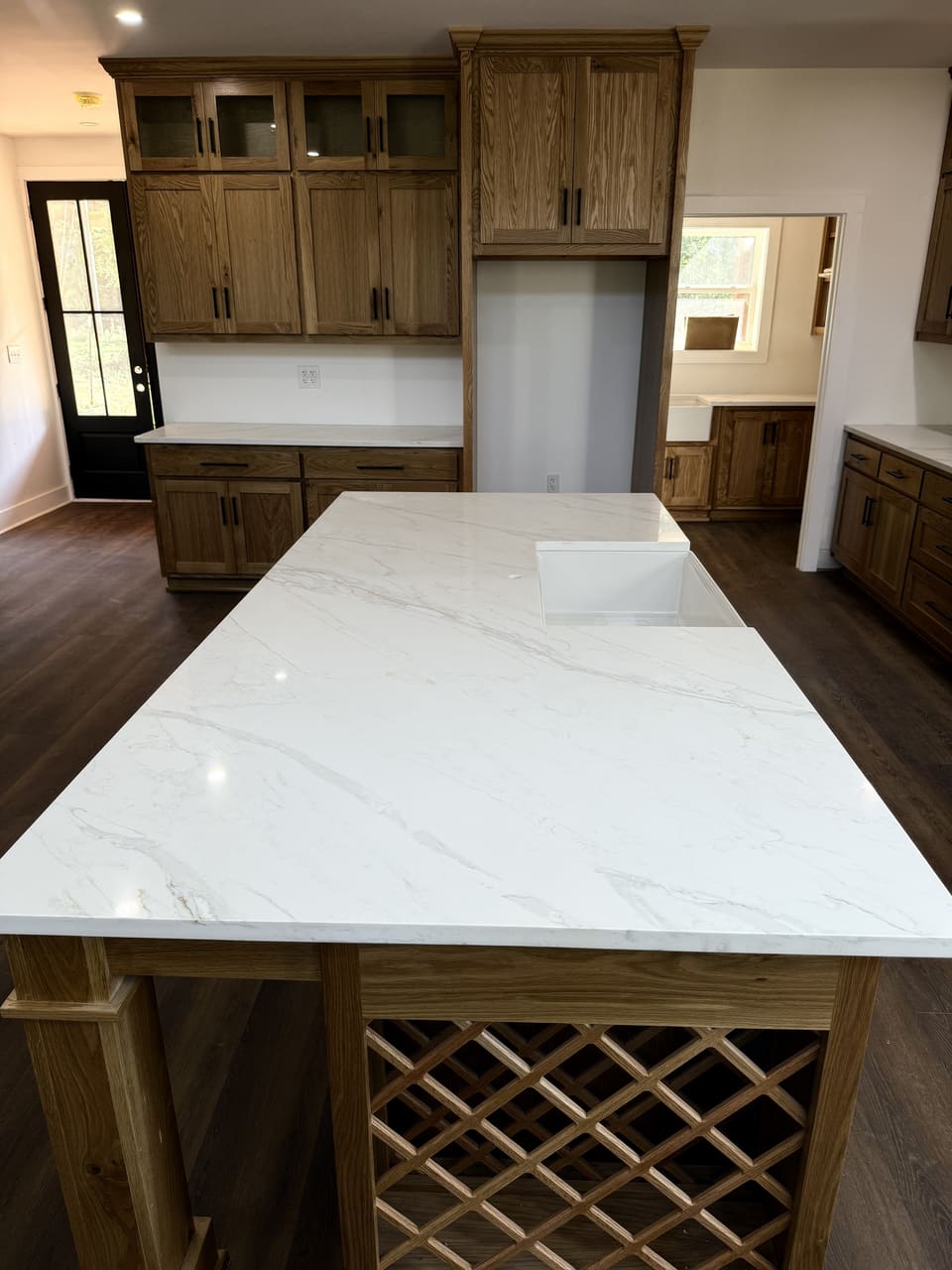 White veined island countertop over an oak base with a lattice wine rack