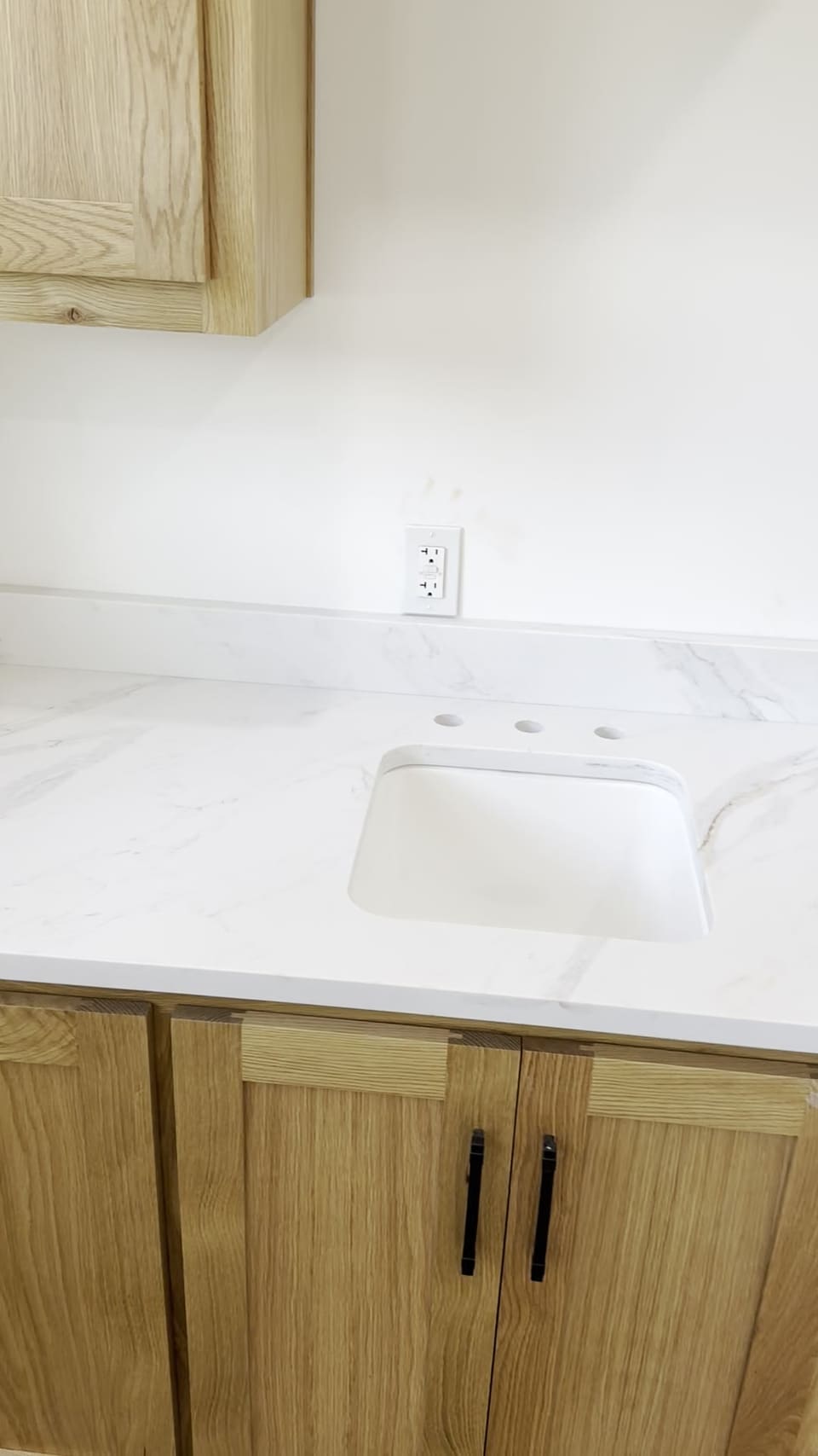 White veined vanity top with an undermount sink over light oak cabinets