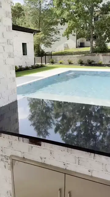 Black stone outdoor kitchen beside a backyard pool