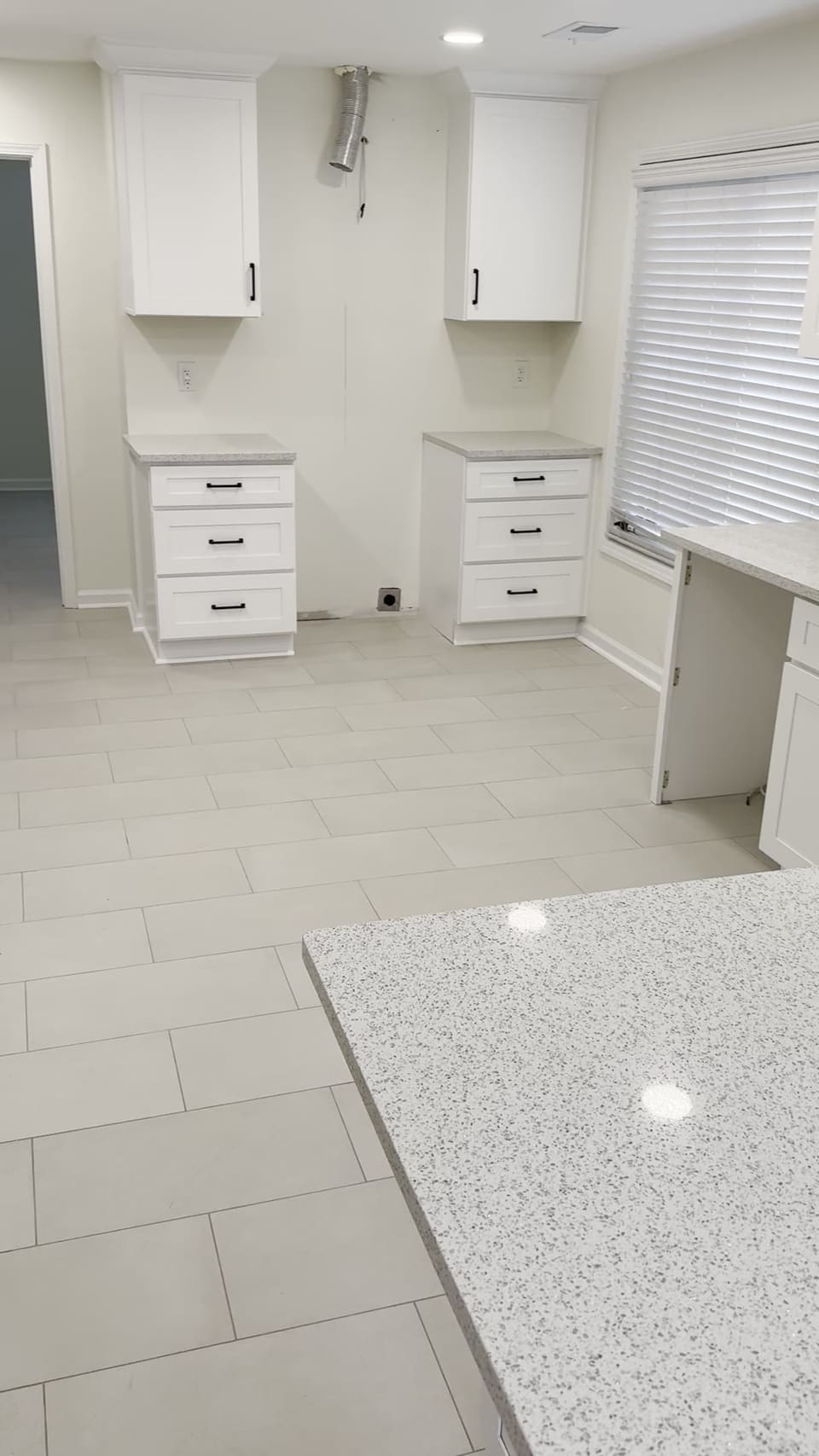 Speckled white countertops on white cabinets in a bright open kitchen