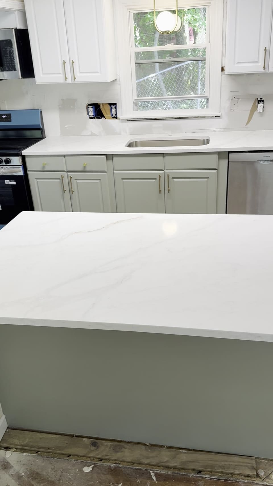 White veined island countertop on sage green cabinets with a matching perimeter and undermount sink